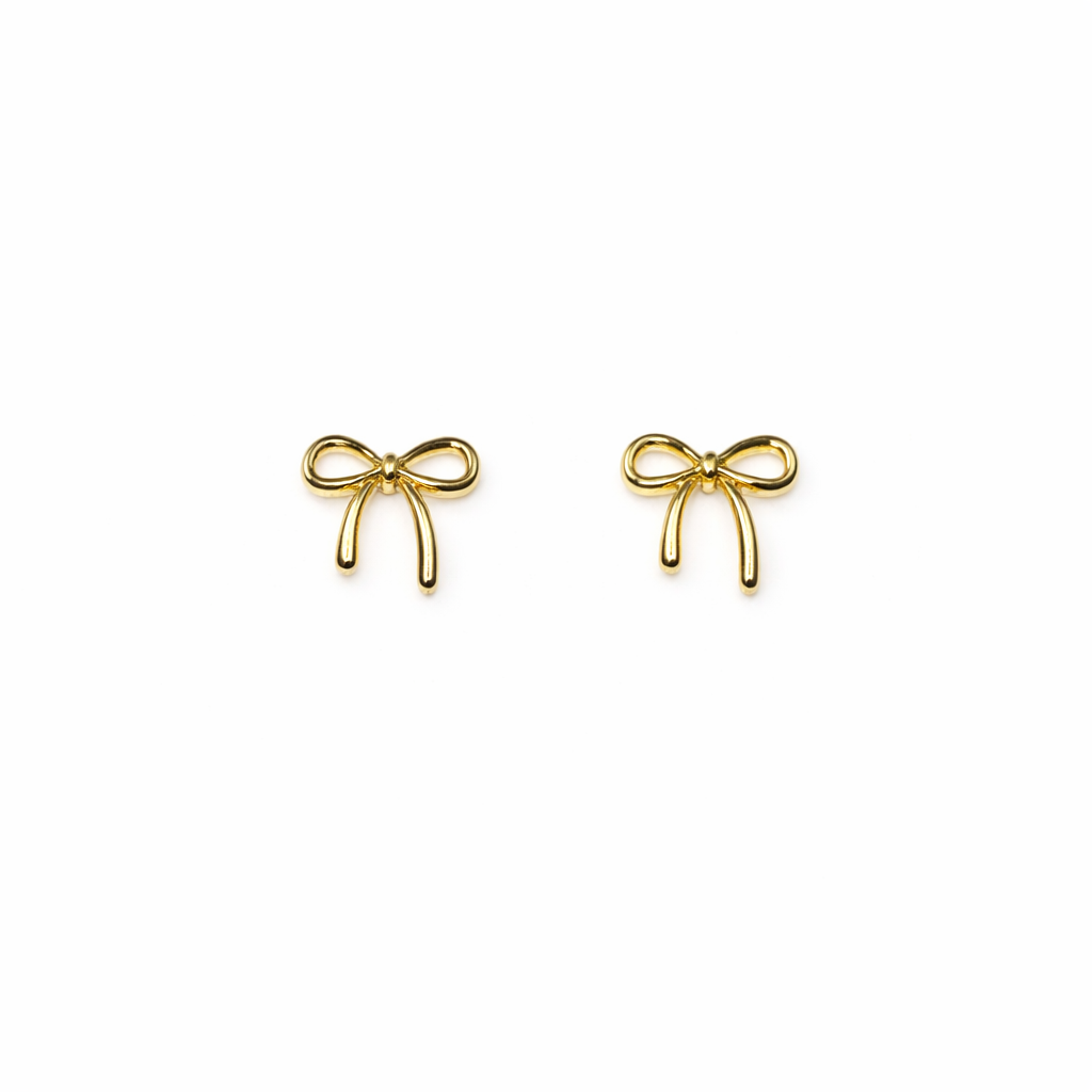 Set of gold bow-shaped nail charms on a white background