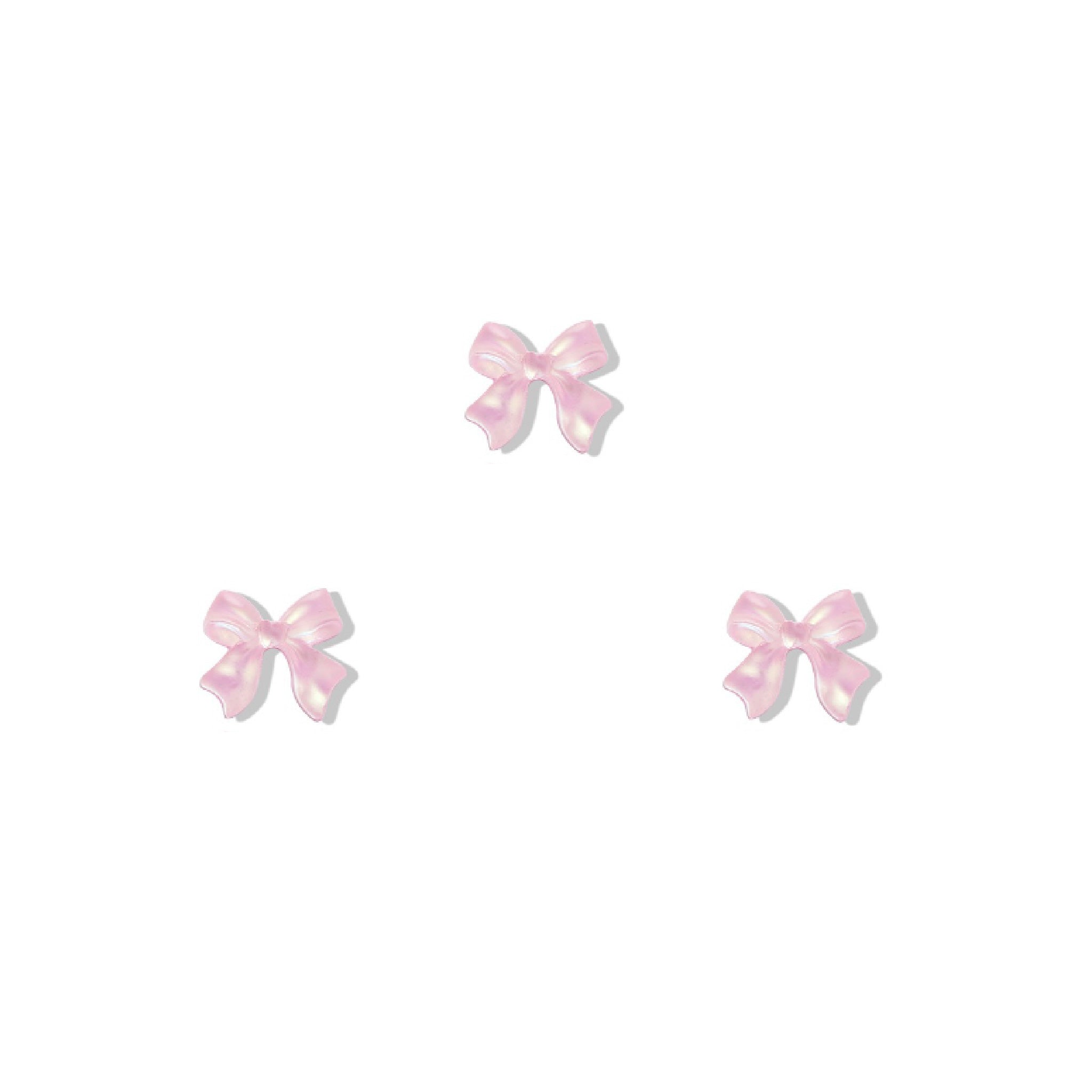 Set of three pink bow-shaped nail charms on a white background